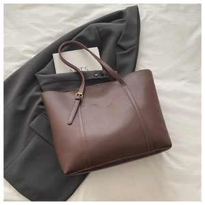 Detailed view of deep brown leather tote bag texture and gold buckle on stylish strap