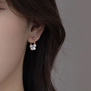 Boucles d'oreilles cœur papillon dorées avec perles portées par un mannequin femme