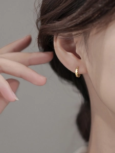 Gros plan sur la boucle d'oreille anneau dorée à motifs géométriques hexagonaux