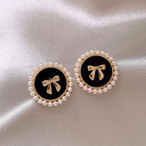 Vue macro de boucles d'oreilles vintage avec centre noir, nœud doré et bordure en perles