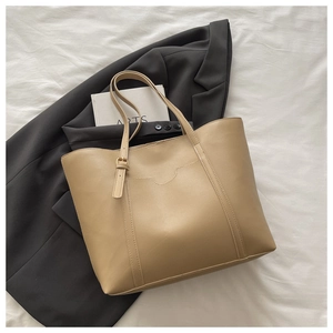 Flat lay of a beige leather tote bag with vertical stitching and adjustable handles