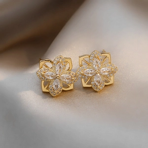 Vue macro de boucles d'oreilles fleurs dorées avec zircons sur satin de champagne