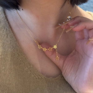 Gold necklace with hollow five-petal flower pendants and a delicate tassel chain