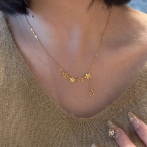 Elegant gold necklace featuring five hollow star charms and a delicate tassel pendant