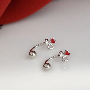 Gros plan sur boucle d'oreille trèfle asymétrique avec émail rouge et motif cœur