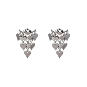 Détail des boucles d'oreilles cœur argentées avec franges métalliques polies et breloques