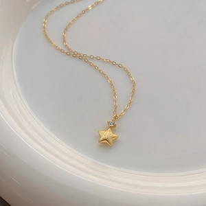 Macro view of gold star pendant necklace with frosted texture and small zircon inlay