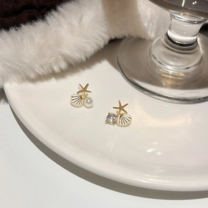 Détail de boucles d'oreilles asymétriques avec étoile de mer coquillage et perle