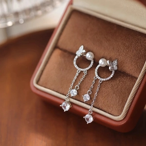 Boucles d'oreilles papillon en argent avec perles et zircons sur présentoir velours