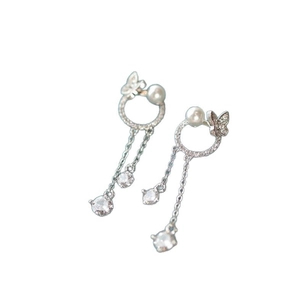 Boucles d'oreilles papillon argentées avec perles et cristaux sur fond blanc épuré