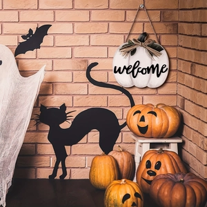 Detail of white pumpkin welcome sign with bat silhouettes and ghost decor on brick wall