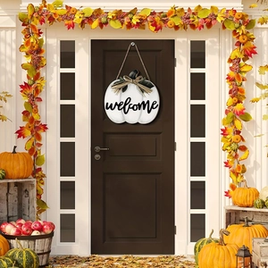 Detail of white pumpkin welcome sign with burlap bow hanging on a rustic wooden front door