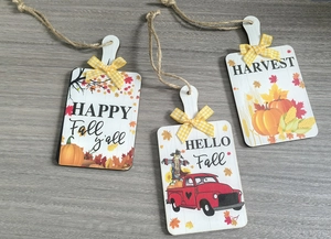 Close-up of wooden autumn door hangers with harvest graphics and plaid bows for fall decor