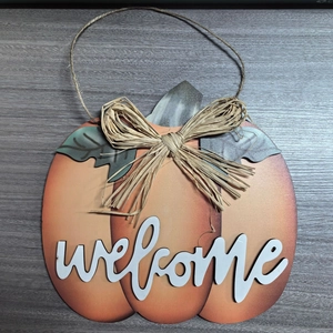 Detail of harvest pumpkin welcome sign with raffia bow and rustic wood texture