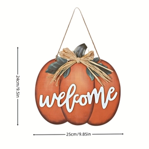 Detail of orange pumpkin welcome sign with green leaves and straw bow for door decor
