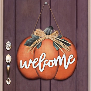 Harvest pumpkin welcome sign hanging on a dark wood door for Thanksgiving fall decor