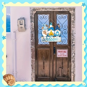 Detail of wooden welcome sign featuring three ocean-themed gnomes on a rustic door