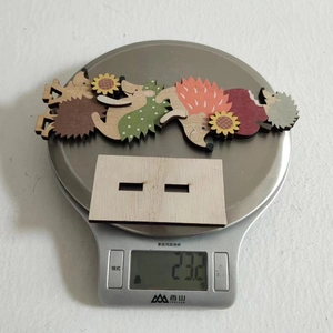 Detail showing wooden hedgehog figurines with sunflowers on an electronic scale for weight check