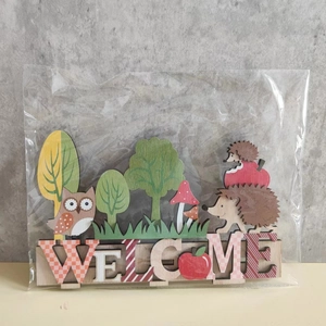 Detail of wooden WELCOME sign with cute hedgehog and owl harvest festival decorations