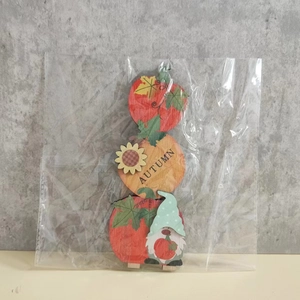 Detail of wooden autumn gnome ornament with pumpkins and sunflower in plastic packaging