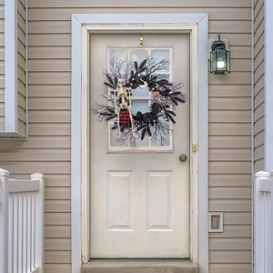 Halloween wreath with skeleton and pumpkin vine on white door with glowing wall lamp