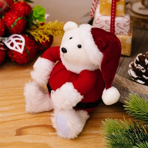 Close-up of a white plush Christmas bear in a red Santa suit with festive holiday decor