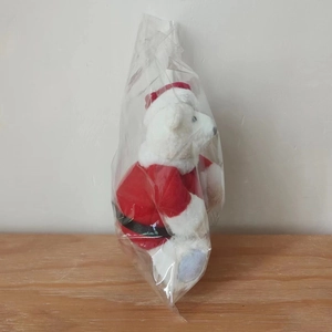 Detail of a white plush Christmas bear in a red outfit wrapped in clear protective packaging