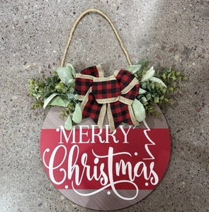 Detail of wooden Christmas door sign with red plaid bow and green foliage accents