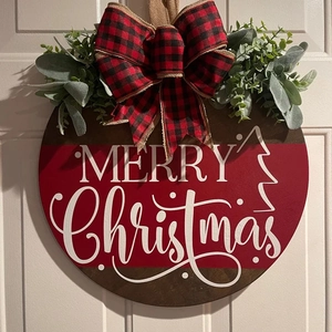 Close-up of wooden Christmas door sign with buffalo plaid bow and greenery on white door