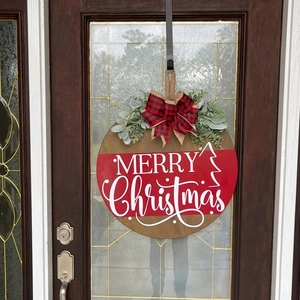 Detail of wooden Merry Christmas sign with buffalo plaid bow on a rustic door