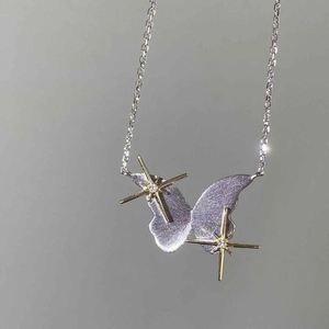 Close-up of butterfly star pendant with silver brushed texture and gold accents