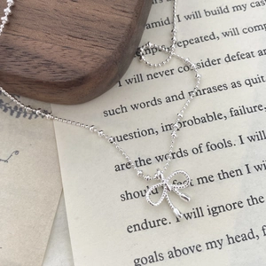 Élégant collier nœud papillon argenté avec texture tressée et chaîne à billes pour femme