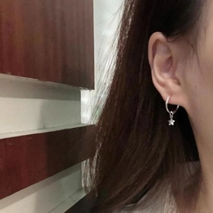 Gros plan d'une boucle d'oreille étoile en argent portée avec un style élégant français