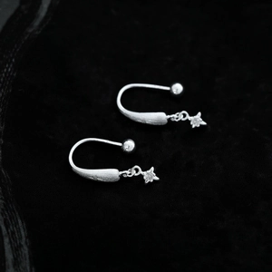 Orecchini a stella in argento spazzolato con micro-diamanti su sfondo nero