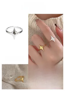 Detail of adjustable star ring in gold and silver showing the four-pointed star design