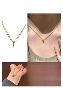 Détail du collier double couche doré de style français avec pendentifs cercle et goutte