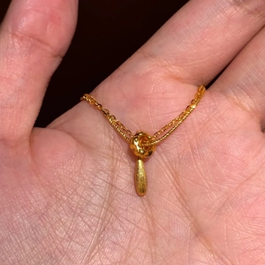 Détail d'un collier doré double épaisseur avec pendentif goutte d'eau texturé chic