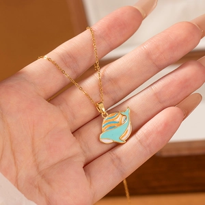 Detail of hand holding a gold fish pendant necklace with blue and orange enamel
