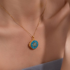 Detail of vintage gold sunburst locket necklace with blue enamel on a female model