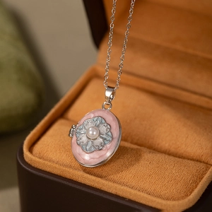 Detail of vintage oval locket pendant with pink enamel and intricate silver flower patterns