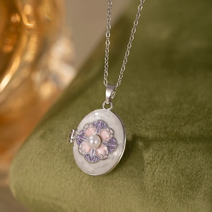 Detailed macro view of vintage silver locket with pink floral enamel and pearl detail
