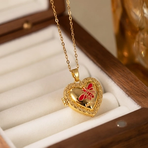Detail of vintage heart locket necklace with red enamel bee and MINE engraving