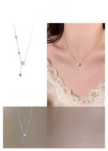 Detail of silver clover tassel necklace with crystal cylinder and butterfly charms