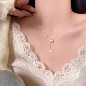 Detailed view of gold clover necklace with tassel pendant and shimmering zircon accents