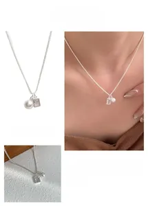 Detail of silver clavicle chain with rectangular zircon and round white pearl pendant