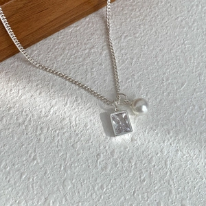 Elegant silver necklace with square zirconia and pearl pendant on textured background