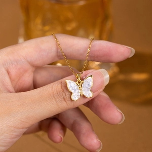 Close-up of golden butterfly necklace with iridescent wings and a zircon center