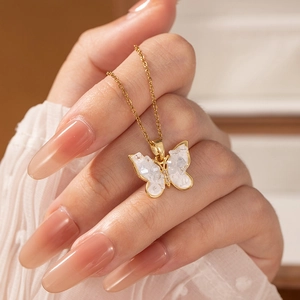 Elegant butterfly pendant necklace with white crystals and gold chain shown on a hand