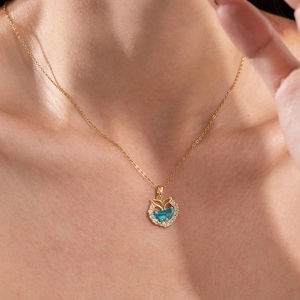 Golden necklace with blue zircon whale tail pendant worn on a model's neck