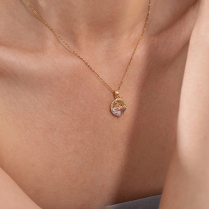 Detail of gold necklace with star and moon charms on a round purple stone pendant